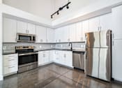 Thumbnail 7 of 8 - A kitchen with white cabinets and a stainless steel refrigerator at Judson Mill Lofts, South Carolina