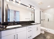 Thumbnail 8 of 8 - A modern bathroom with a large mirror, sink, and glass shower stall at Judson Mill Lofts, Greenville, South Carolina