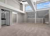 Thumbnail 20 of 22 - an empty living room with windows and a kitchen at Spinning Mill Lofts, Clayton, NC 27520