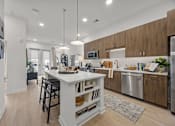 Thumbnail 1 of 63 - A modern kitchen with a white island and wooden cabinets.at Adler Montford Park + Drexel Townes, Charlotte, NC, 28209