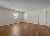 Thumbnail 2 of 10 - the spacious living room of an empty home with wood flooring and a window