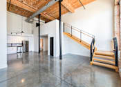 Thumbnail 6 of 8 - A large open space with a staircase and a kitchen area at Judson Mill Lofts, Greenville