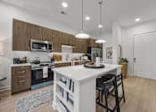 Thumbnail 2 of 63 - A modern kitchen with a white island and wooden cabinets.at Adler Montford Park + Drexel Townes, Charlotte, NC, 28209