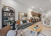 Thumbnail 5 of 63 - A living room with a grey couch, a coffee table, and a bookshelf.at Adler Montford Park + Drexel Townes, Charlotte, NC, 28209