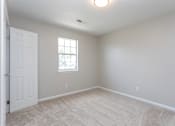 Thumbnail 15 of 21 - A room with a carpeted floor, a window, and a door.