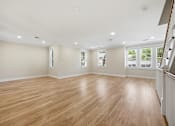 Thumbnail 25 of 63 - A spacious room with wooden flooring and white walls.