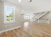 Thumbnail 21 of 63 - A spacious room with wooden floors and a staircase.