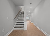 Thumbnail 22 of 30 - A long hallway with a staircase and wooden floors.at Regency Townes, Winterville, 28590  