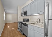 Thumbnail 4 of 10 - an empty kitchen with white cabinets and stainless steel appliances