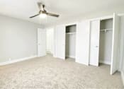 Thumbnail 11 of 13 - A room with a ceiling fan and carpeted floor.