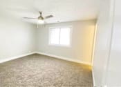 Thumbnail 10 of 13 - A room with a carpeted floor, a ceiling fan, and a window.