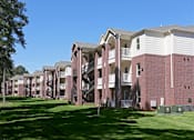 Thumbnail 1 of 13 - Apartment complex with red brick buildings and green lawns.