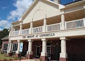 Thumbnail 6 of 13 - The Greens at Longhills is a building with a red brick exterior and a white overhang.