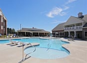Thumbnail 9 of 13 - A large swimming pool with a slide and sun loungers in front of a building.