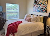Thumbnail 15 of 21 - A bed with a red blanket and pillows in a room.