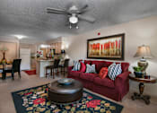 Thumbnail 14 of 27 - A living room with a red couch and a ceiling fan.