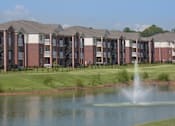 Thumbnail 1 of 22 - A row of apartment buildings with a fountain in front.