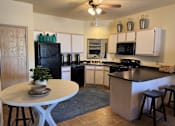 Thumbnail 3 of 21 - A kitchen with a black fridge and white cabinets.