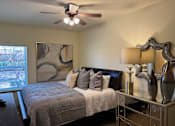 Thumbnail 5 of 21 - A bedroom with a bed, nightstand, and a painting on the wall.