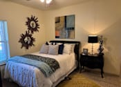 Thumbnail 10 of 21 - A bedroom with a bed, a nightstand, and a painting on the wall.
