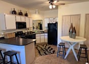 Thumbnail 13 of 21 - A kitchen with a black counter top and white cabinets.