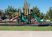 Thumbnail 17 of 21 - A playground with a green slide and a brown wooden structure.
