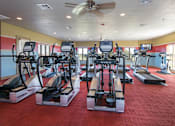 Thumbnail 18 of 21 - A gym with treadmills and elliptical machines.