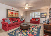 Thumbnail 1 of 11 - a living room with red couches and a rug and a ceiling fan