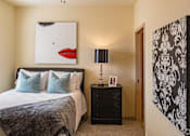 Thumbnail 13 of 21 - A bedroom with a large bed and a painting of a red mouth above it.