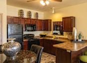 Thumbnail 12 of 21 - A kitchen with a black refrigerator and wooden cabinets.