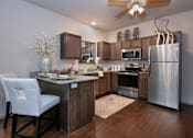 Thumbnail 7 of 14 - A modern kitchen with a white chair and wooden cabinets.