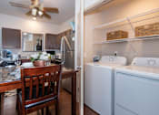 Thumbnail 8 of 14 - A kitchen with a table and chairs and a laundry room with a washer and dryer.