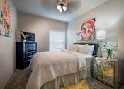 Thumbnail 9 of 14 - A bedroom with a bed, dresser, and a painting on the wall.