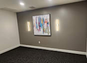 Thumbnail 16 of 36 - Empty room with abstract art and wall sconces at 68 Beale Apartments, Quincy