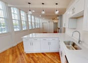 Thumbnail 75 of 96 - A kitchen with white cabinets and a wooden floor.