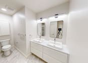 Thumbnail 87 of 96 - A white bathroom with a toilet, sink, and mirror.