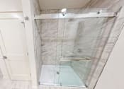 Thumbnail 80 of 96 - A bathroom with a walk-in shower and a white door.