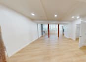 Thumbnail 61 of 96 - A large empty room with wooden floors and white walls.