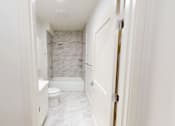 Thumbnail 53 of 96 - A white bathroom with a marble tiled shower.