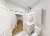 Thumbnail 48 of 96 - A white bathroom with a toilet, sink, and mirror.