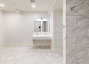 Thumbnail 47 of 96 - A bathroom with a white sink and marble tiles.