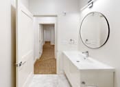 Thumbnail 54 of 96 - A white bathroom with a round mirror and a white sink.