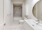 Thumbnail 71 of 96 - A white bathroom with a marble tile shower.