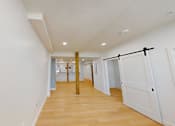 Thumbnail 39 of 96 - A long hallway with a white wall and a wooden floor.