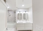 Thumbnail 40 of 96 - A white bathroom with a marble tile shower and a double sink vanity.