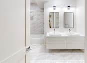 Thumbnail 37 of 96 - A bathroom with two sinks and a marble wall.