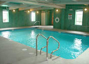 Thumbnail 1 of 12 - A large indoor swimming pool with a ladder on the side.