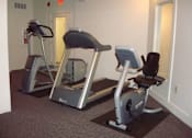Thumbnail 2 of 12 - Two exercise bikes are in a room.