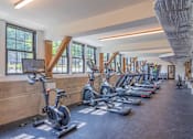 Thumbnail 29 of 53 - A gym with a row of stationary bikes and treadmills.