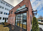 Thumbnail 5 of 53 - The Overlook 44 Wharf is a modern building with a brick facade and large glass windows.
